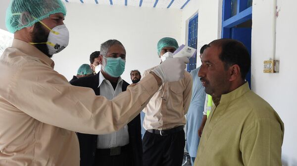 Врач проверяет температуру тела человека, возвращающегося из Ирана в карантинной зоне в пакистано-иранском приграничном городе Тафтан